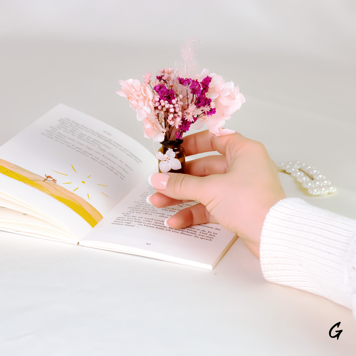 Mini bouquets of dried flowers in delicate glass vase held in woman's hand.