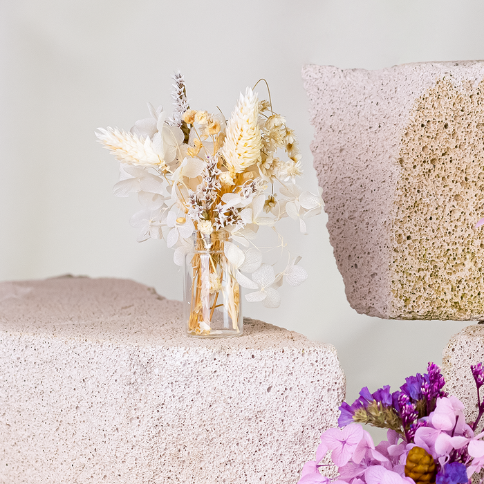 Mini bouquets of dried white and beige flowers in delicate glass vase.