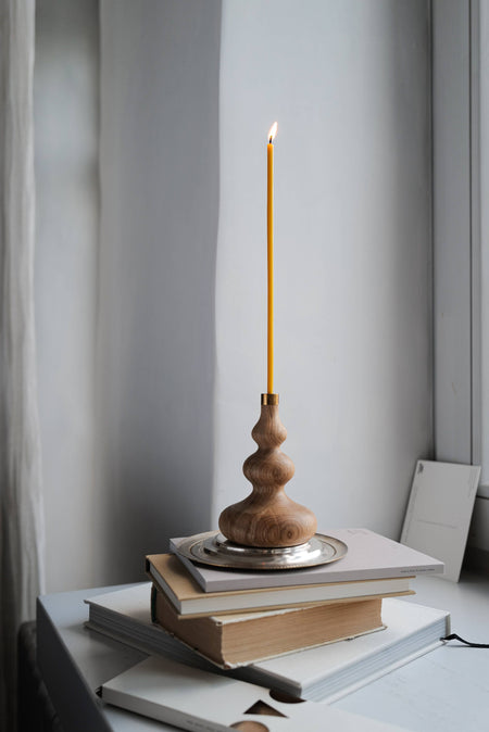 Thin and fine candle in wooden candle holder.