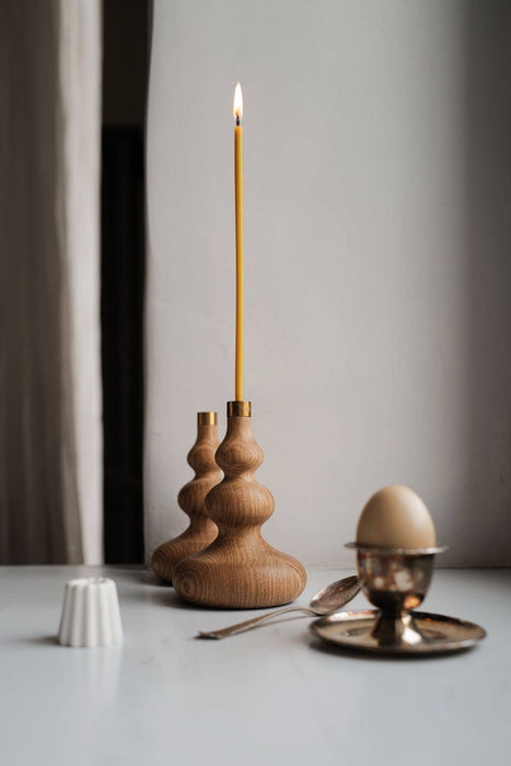 Thin and fine candle in wooden candle holder.
