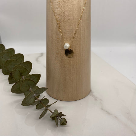 Gold necklace with an initialed charm for personalization.