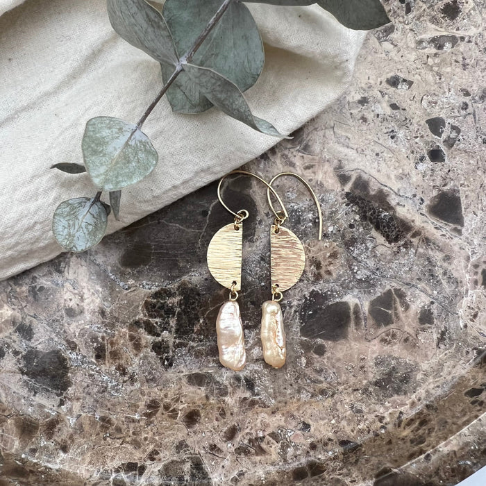 Image shoes dangle earrings made out of 14-K gold-filled material with halfmoon shaped hammered findgs and finished off with differently shaped freshwater pearls.