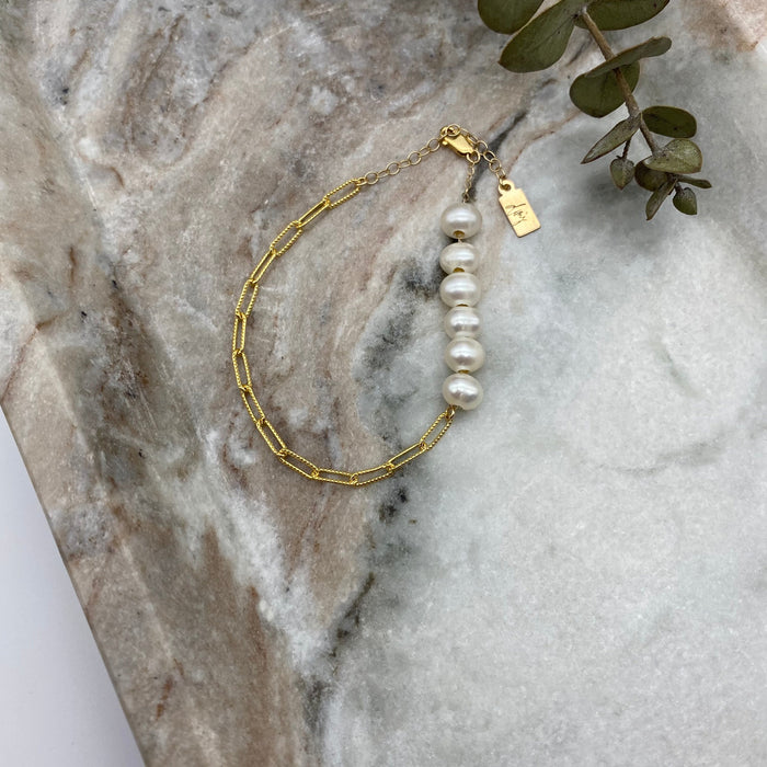 Images shows a 14-K gold-filled chain bracelet adorned by six off-white freshwater pearls.