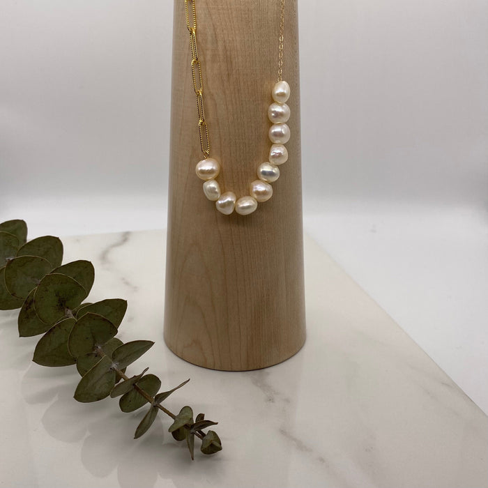 Image shows a 14-K gold-filled necklace with ten off-white freshwater pearls.