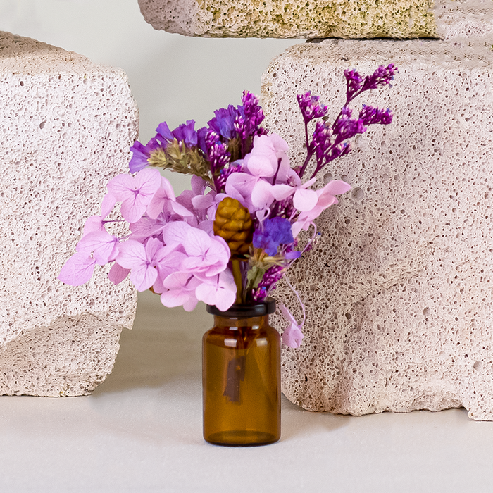 Mini bouquets of dried purple and lavender flowers in delicate glass vase.