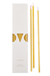 Thin and fine candle with different colored wicks. Package of candles next to three candles that lay outside of the packaging.