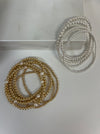 Two sets of beaded bracelets displayed, one set in gold and the other in silver color, arranged in circles on a light background.