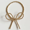 A gold filled bracelet with a bow detail, double strung on elastic, displayed against a neutral background.