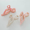 Three ribbon metal bow claw clips in pink, white, and red colors with a gold metal base.