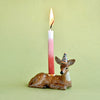 A porcelain deer cake topper with a yellow and blue striped party hat, featuring a gold luster cup with a candle on top.