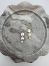 A pair of round freshwater pearl earrings with gold-filled metal hoops, displayed on a marble surface.