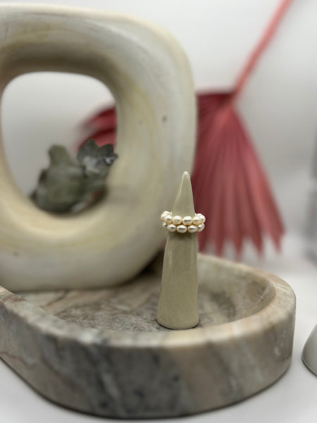 Two all around freshwater pearl rings stacked on top of each other on clay cone.