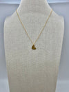 A gold-colored heart necklace displayed on a mannequin bust