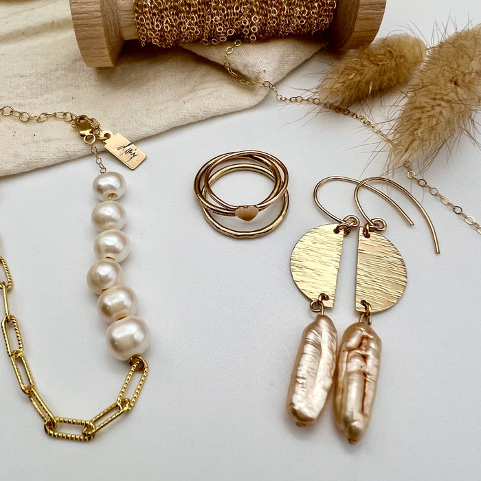 Earrings feature a hammered finish half moon finding and the Biwa freshwater pearl. Dangle earrings next to gold-filed rings, and bracelet with freshwater pearls.