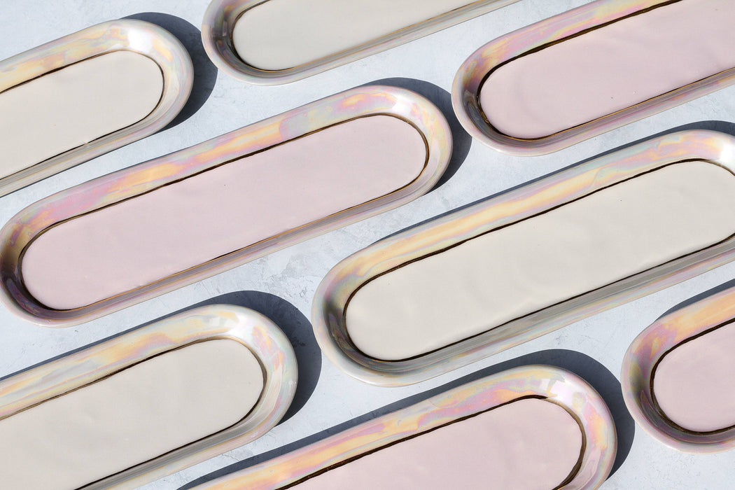 A collection of porcelain trinket dishes with gold edges and opal centers, interspersed on a neutral background.