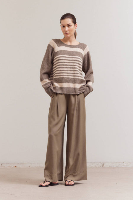 Woman wearing a striped sweater and wide-leg pants against a plain background