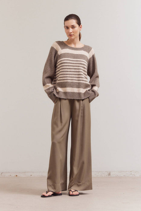 Woman wearing a striped sweater and wide-leg pants against a plain background