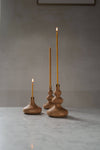 Three oiled oak candle stick holder with brass detail and slim beeswax candles.