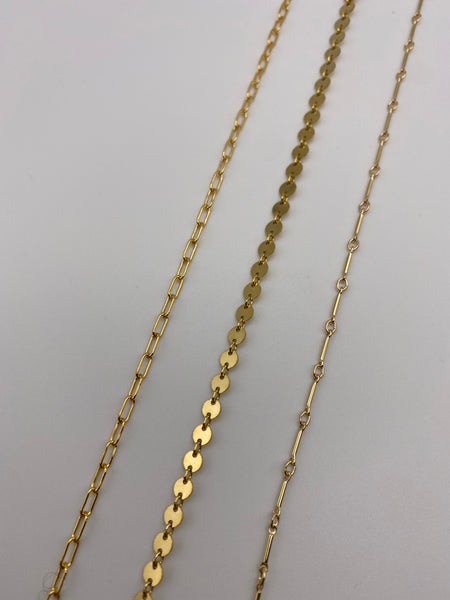 Gold coin chain choker chain in between two other gold chains.