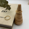 Three 14k gold-filled beaded wire rings. Two stacked on a wood cone and one laying next to it ona raised surface.